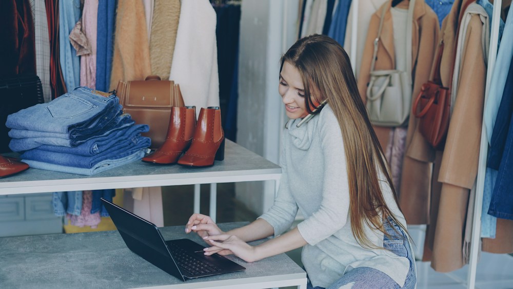 Emprendedora de moda gestionando su negocio desde una laptop en su boutique